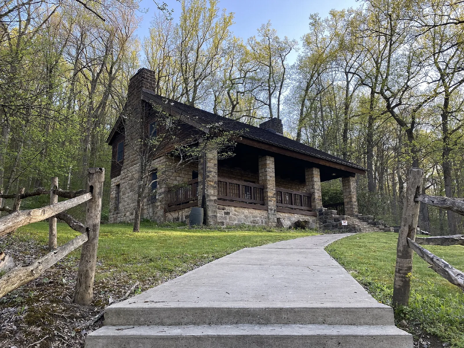 Old stone lodge with porch behind a lawn and walkway