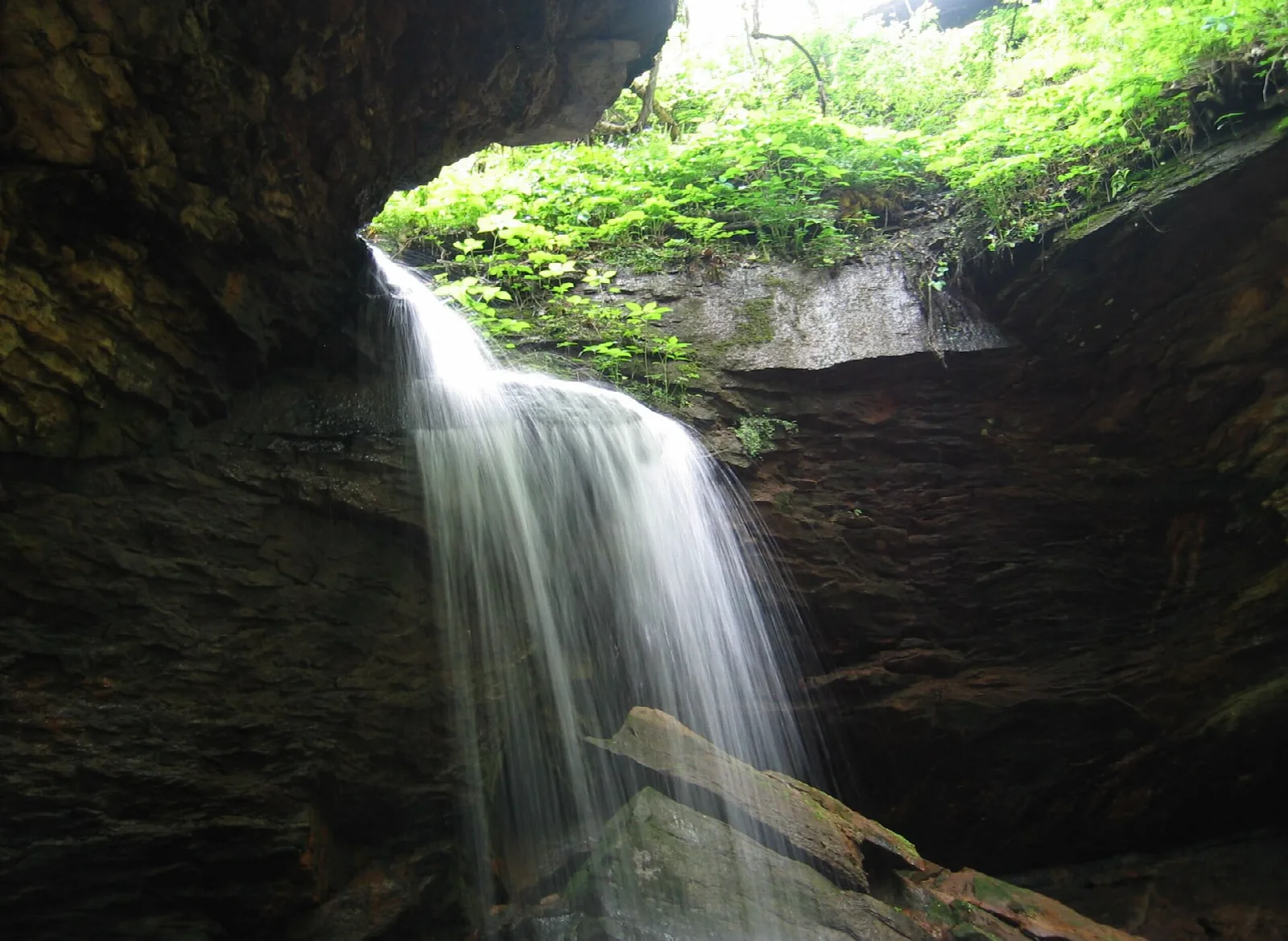 Waterfall dropping into a rocky hollow with green moss above
