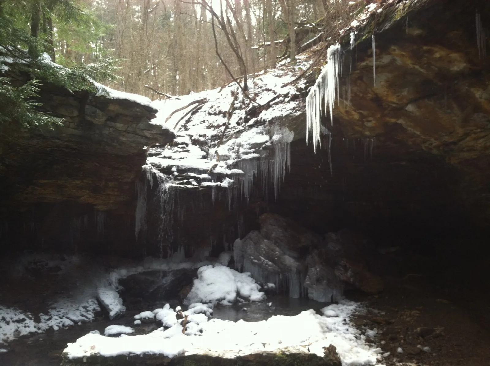 Frozen waterfall in a rock hollow with snow and icicles