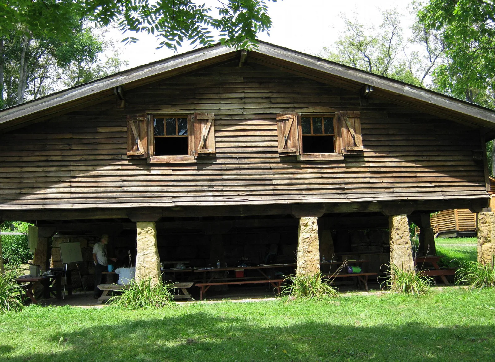 Rustic timber pavilion with stone posts on a green lawn