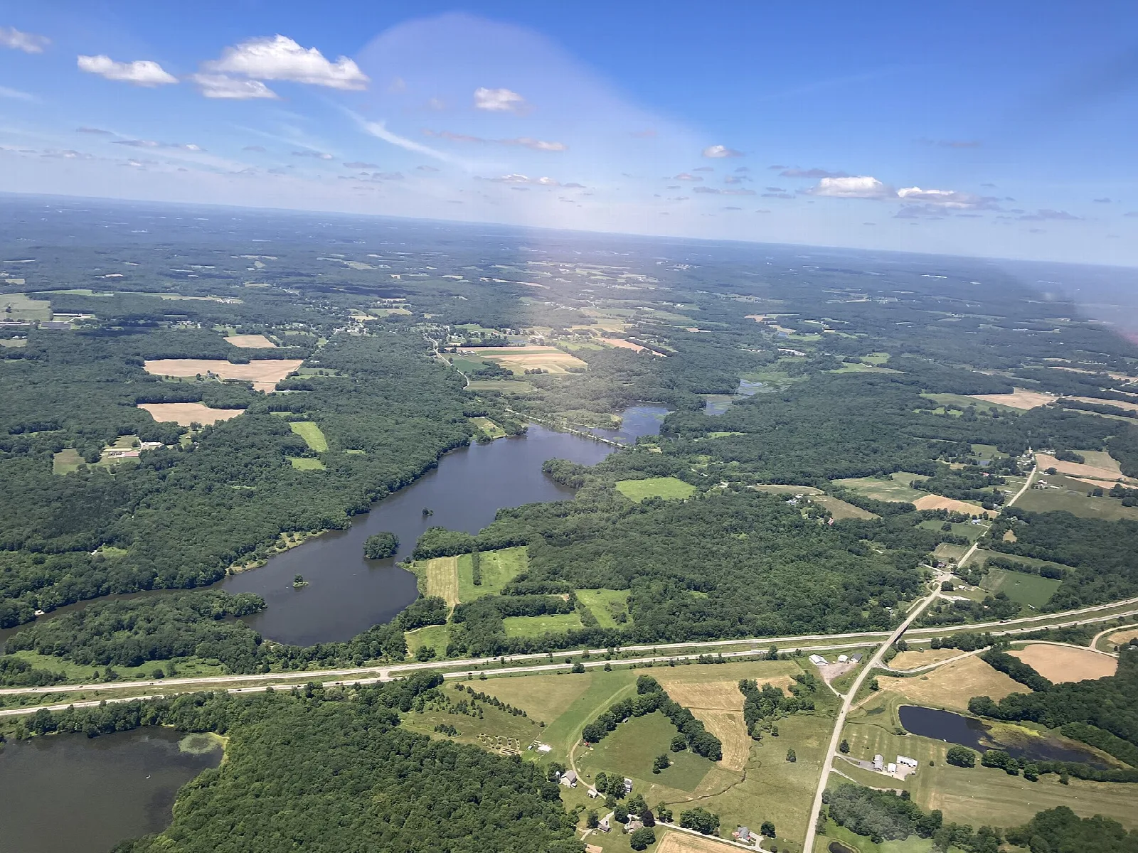 Aerial view of a lake bay beside farmland and a road