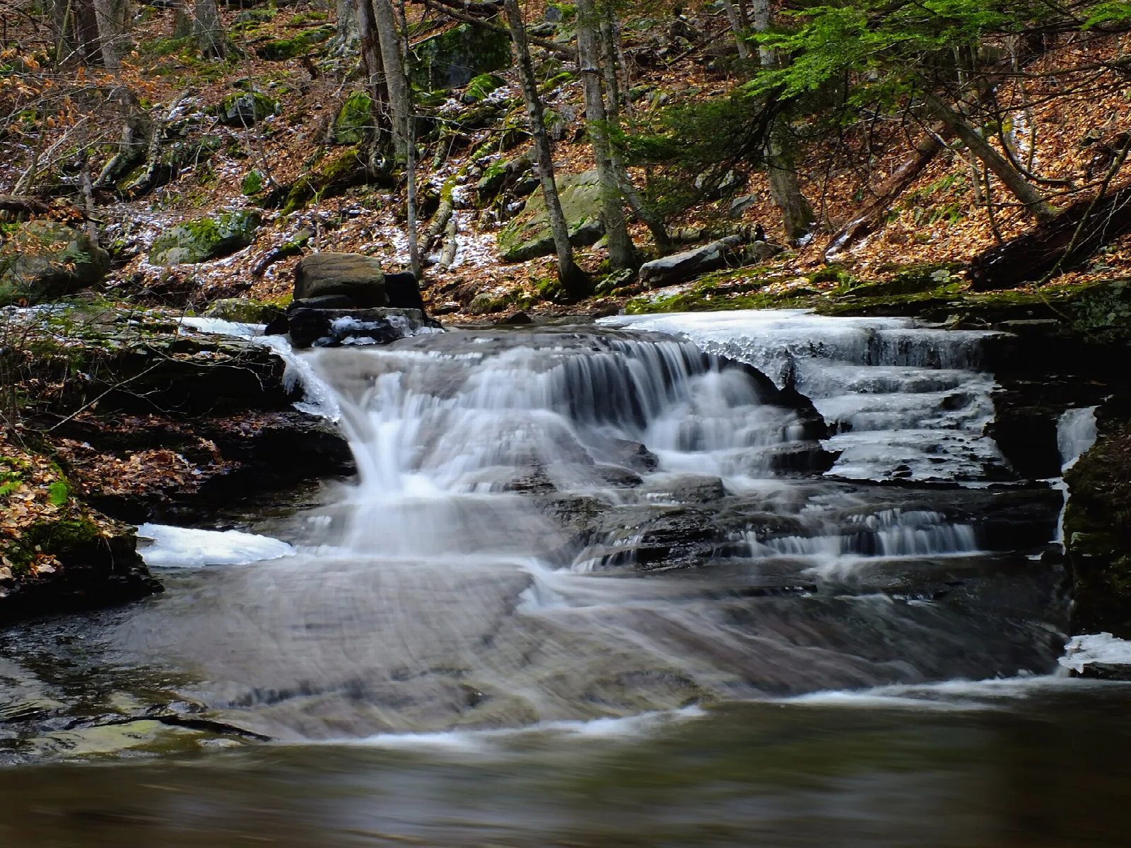 Small waterfall over flat rock in an autumn forest