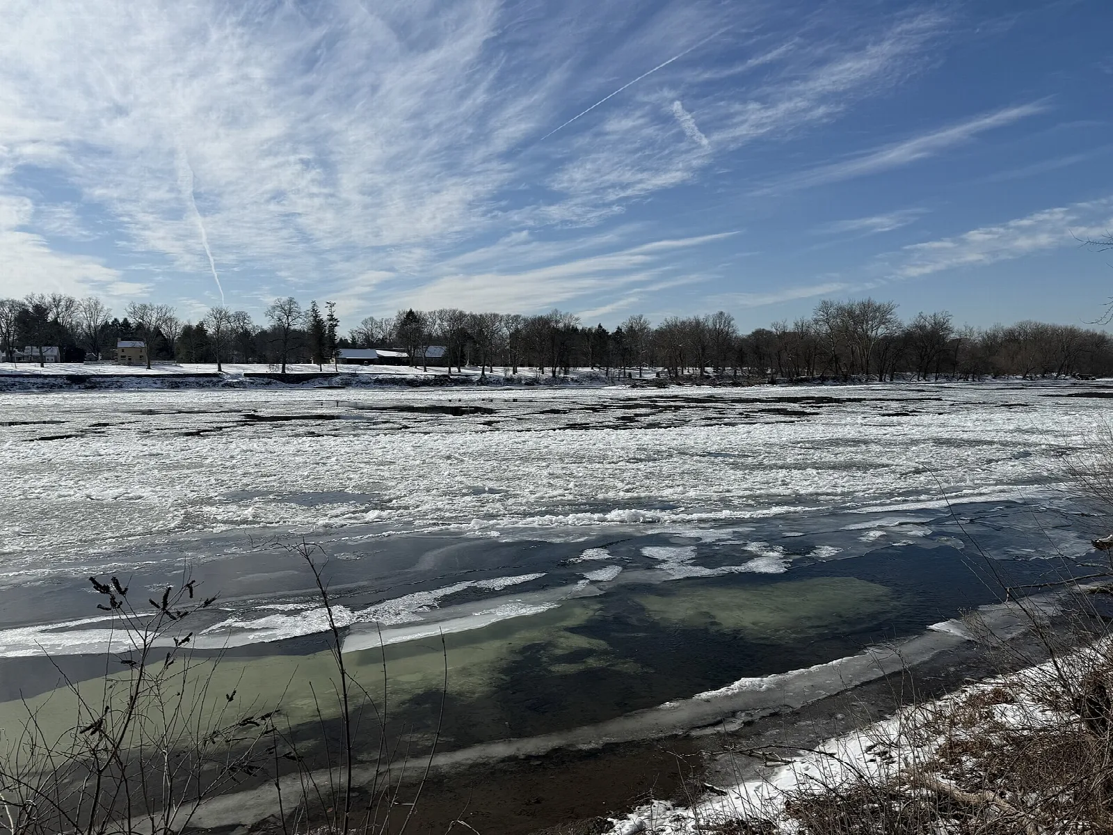 Wide icy river with a distant tree-lined far bank