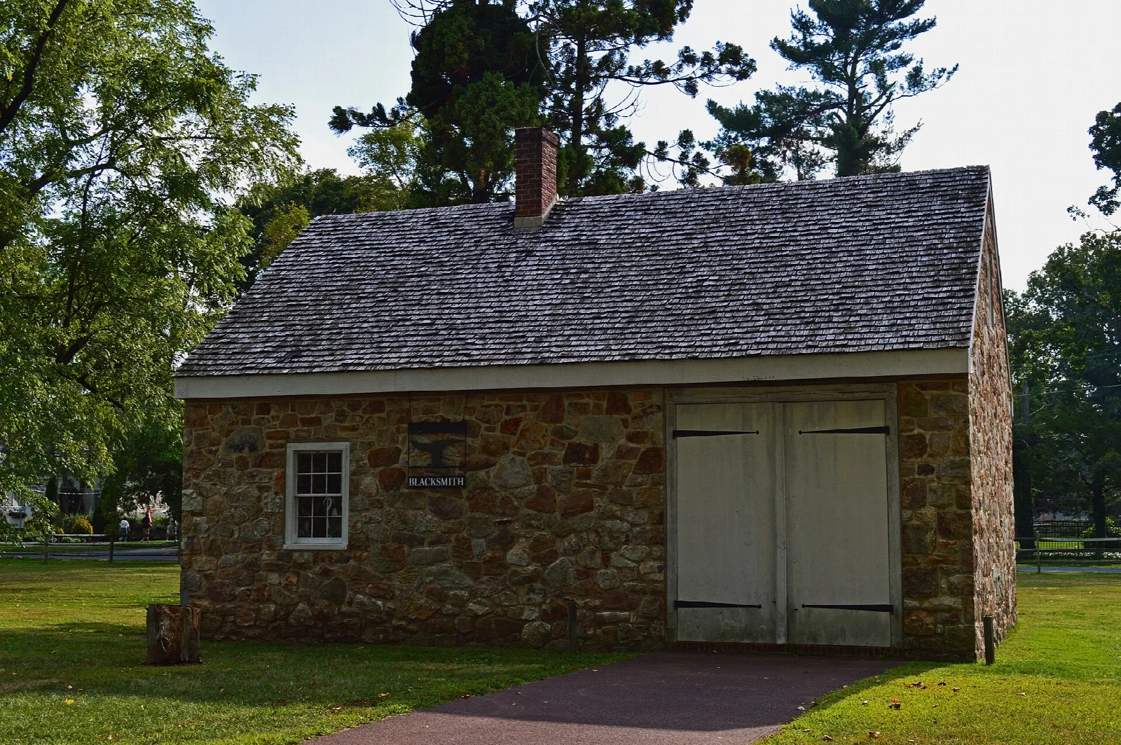 Stone workshop building with large pale doors on a lawn