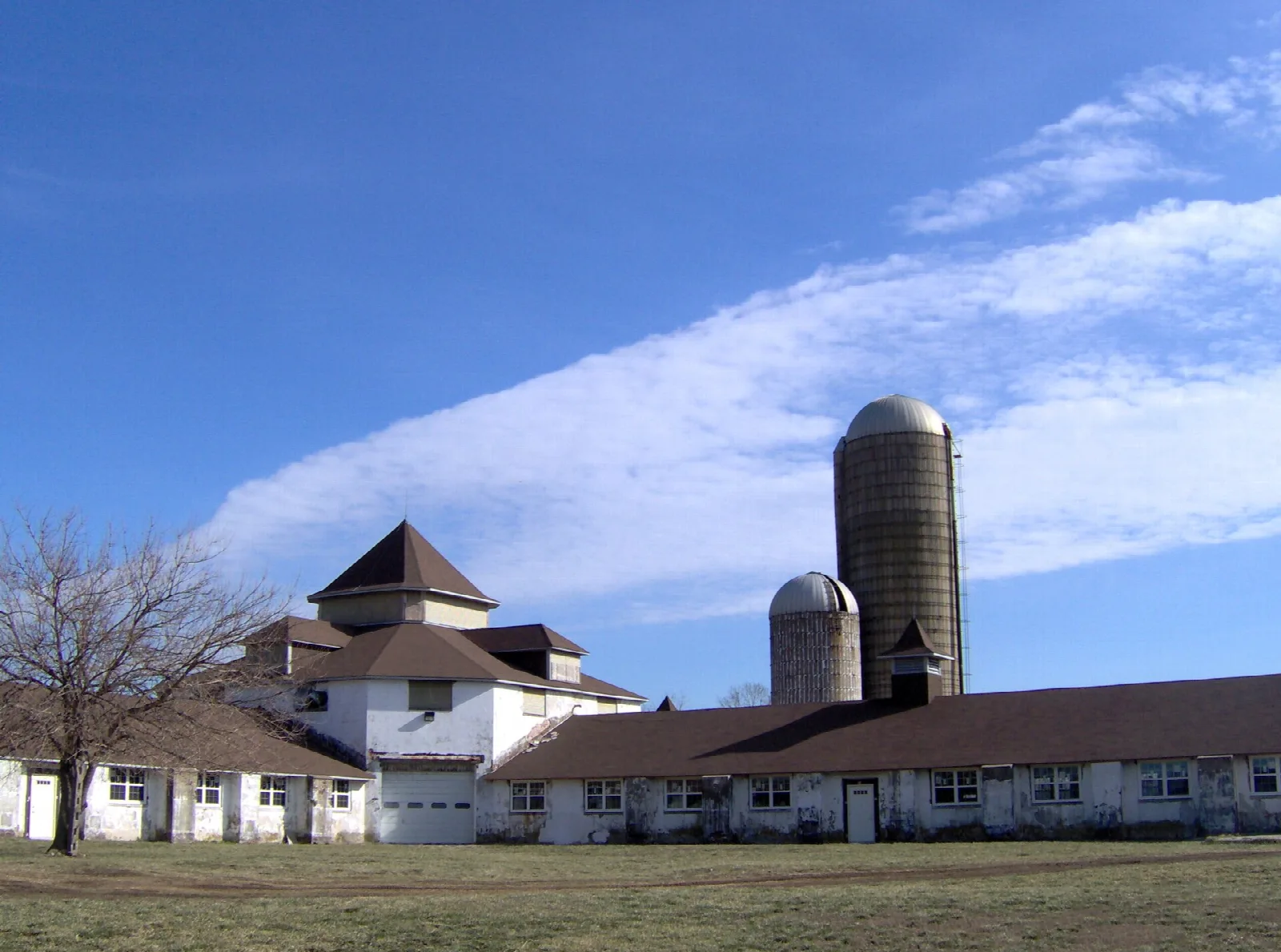 White farm buildings with two silos under a blue sky