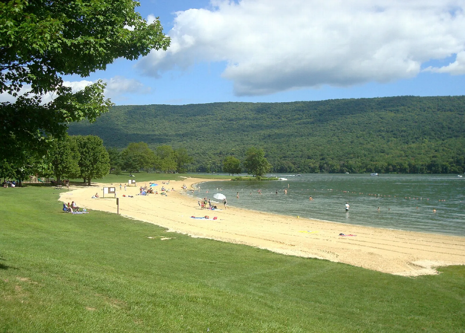 Sandy beach along a lake with forested mountain ridges behind