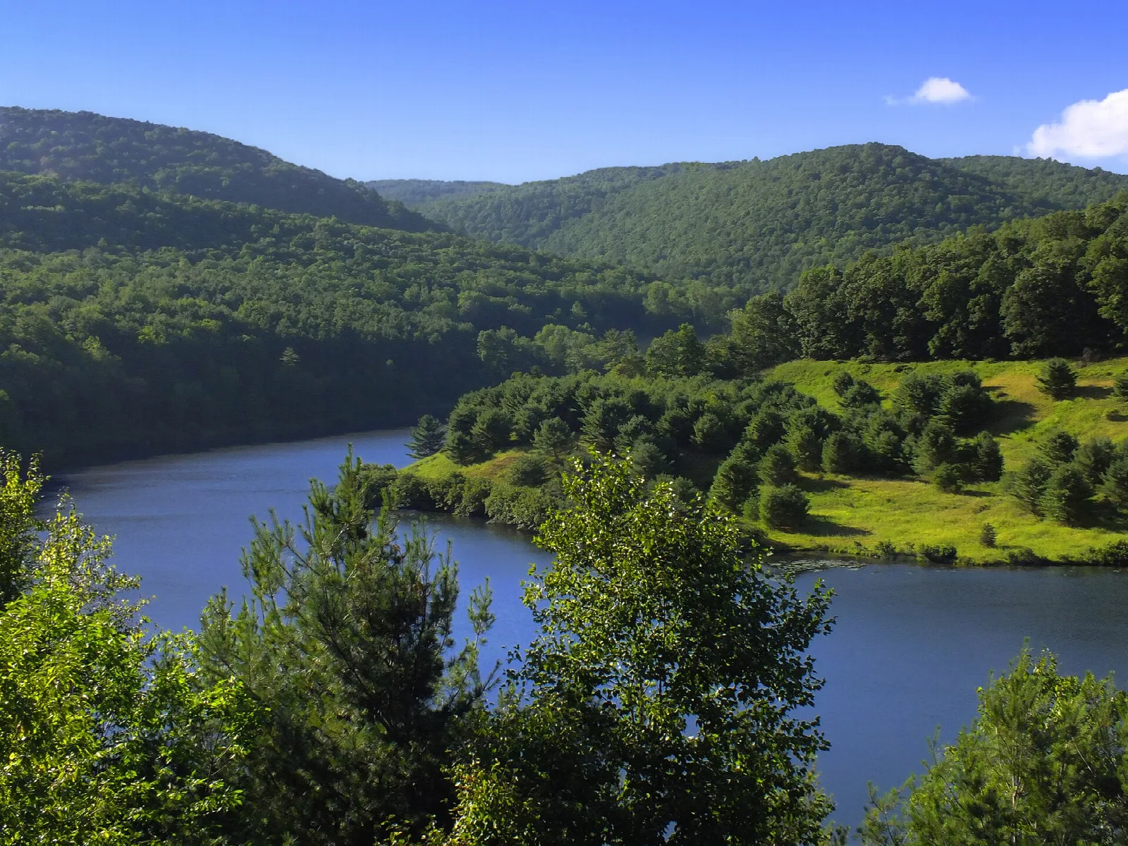 Blue water winding through a green valley with wooded hills beyond