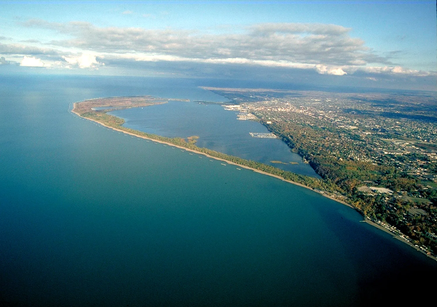 Aerial view of a long curving sandy peninsula along Lake Erie beside a city