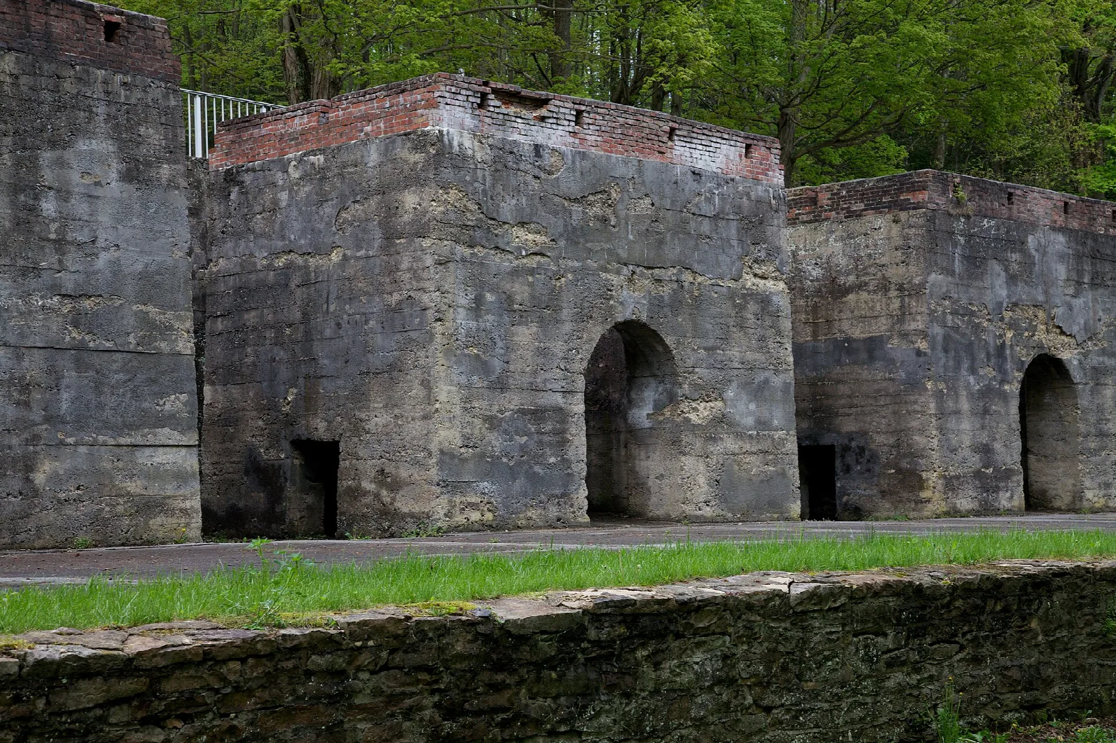 Old stone limekilns with arched openings beside a grassy lawn