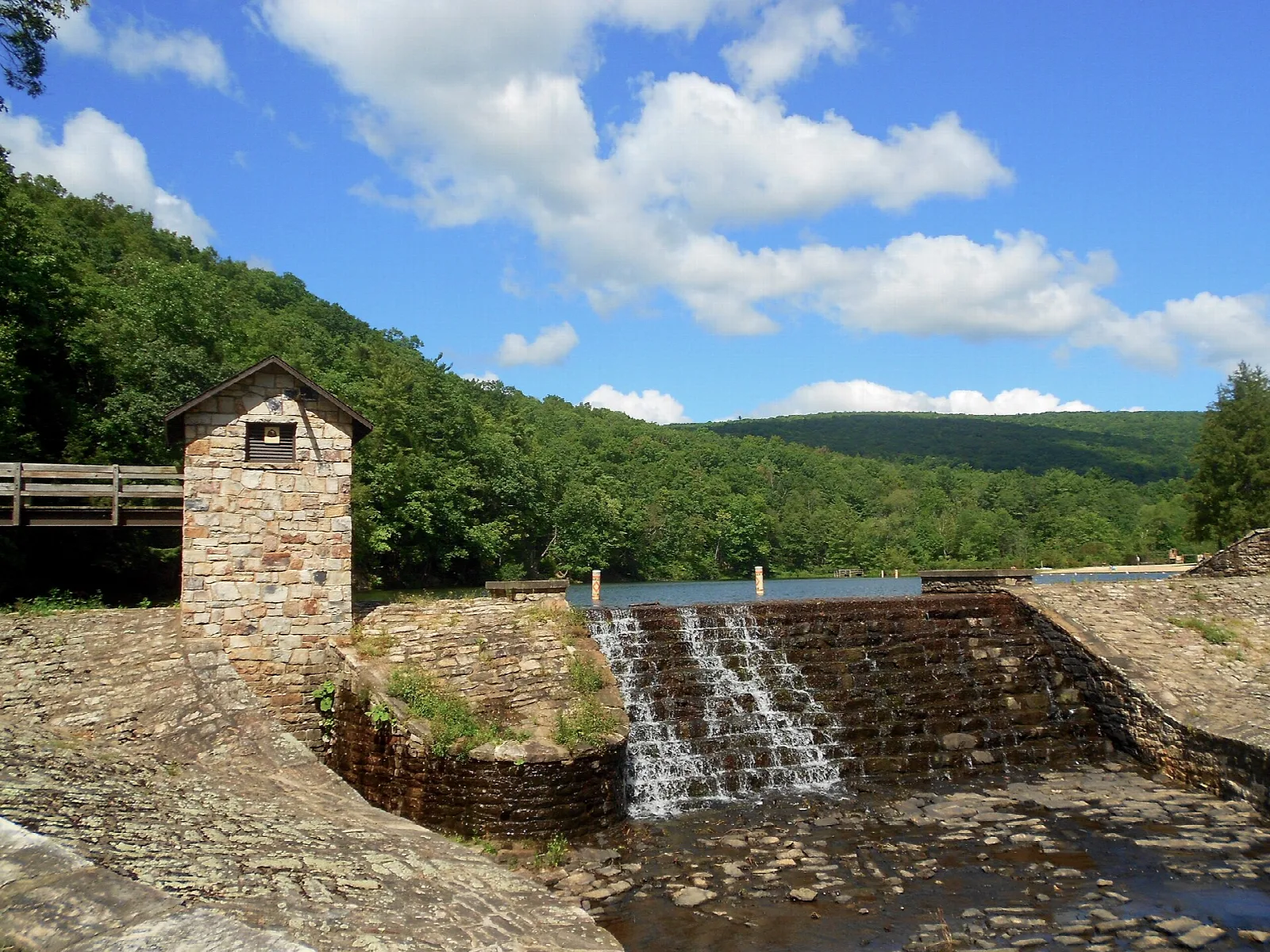 Stepped stone spillway and small stone house under a blue sky