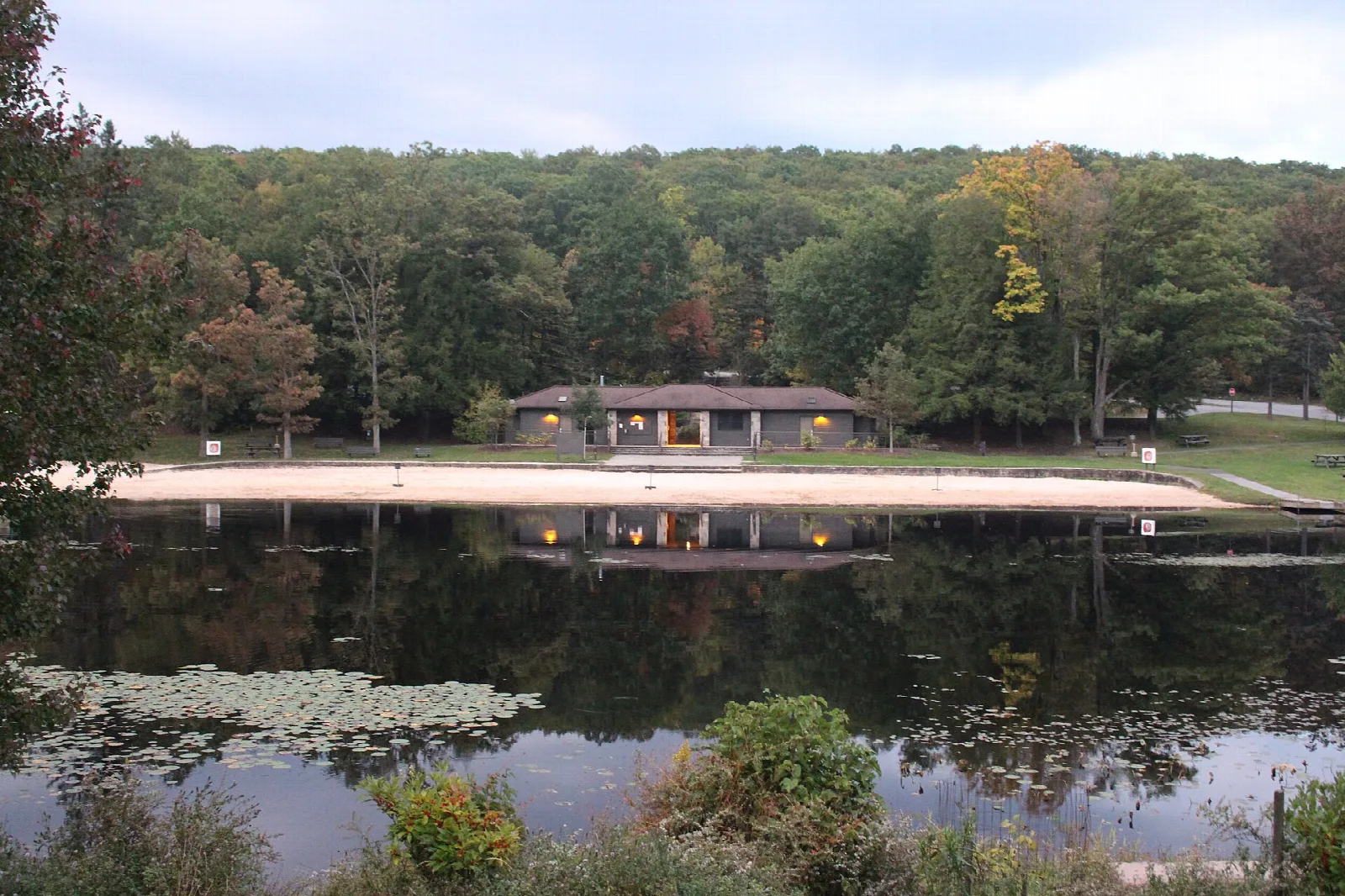 Beach house on a lake shore with forested hills behind