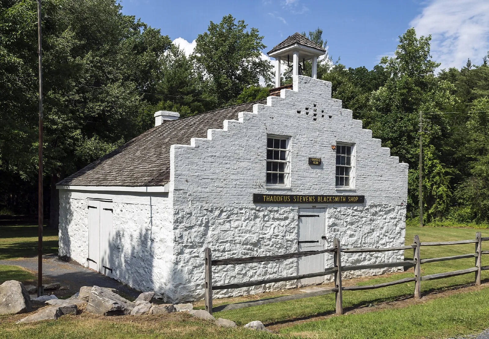 White blacksmith shop building with a fence under a blue sky