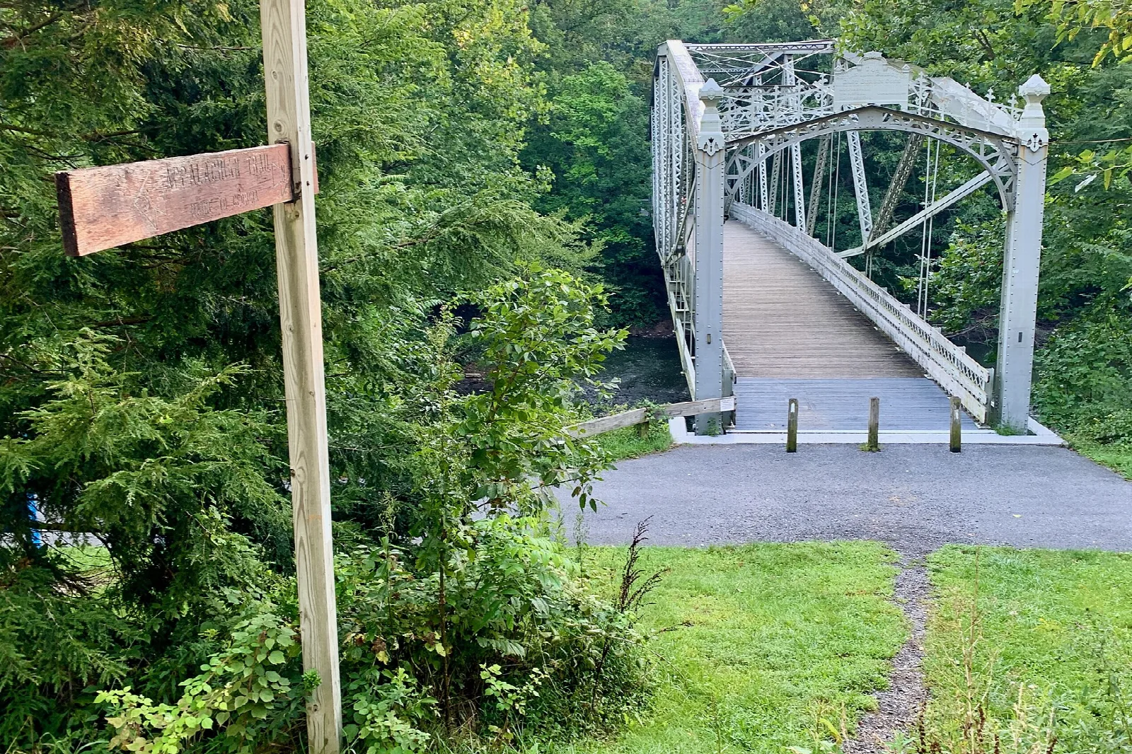 Metal bridge at the end of a trail in green woods