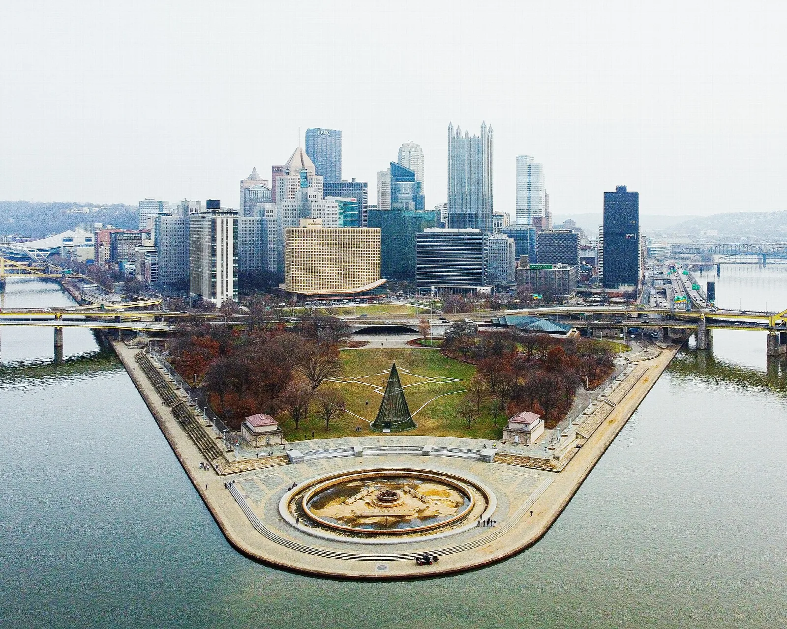 Aerial view of a round fountain at the point of a park with city towers behind