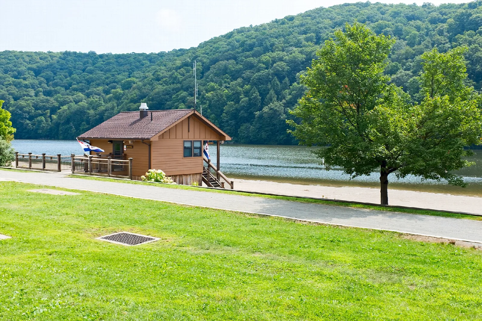 Lakeside building and lawn below a green forested hill