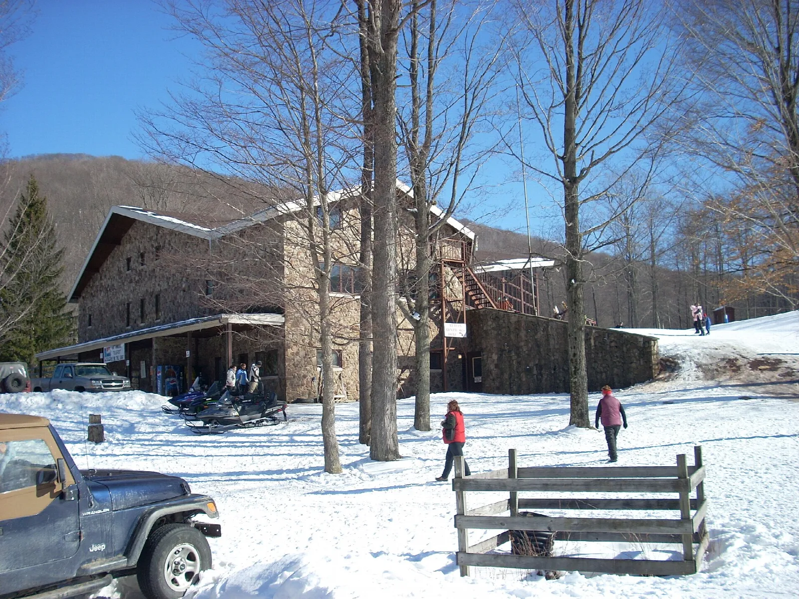 Wooden lodge in winter with a truck parked in the snow in front
