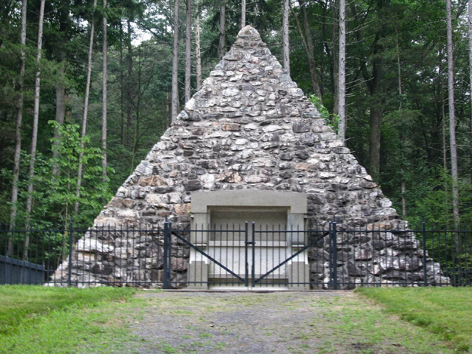 Stone pyramid monument with a gate in a pine forest