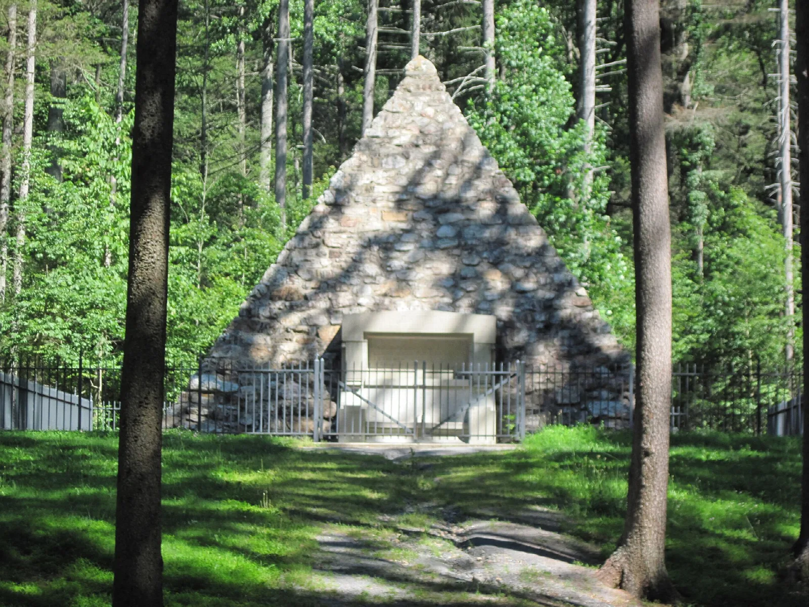 Stone pyramid seen between tall tree trunks