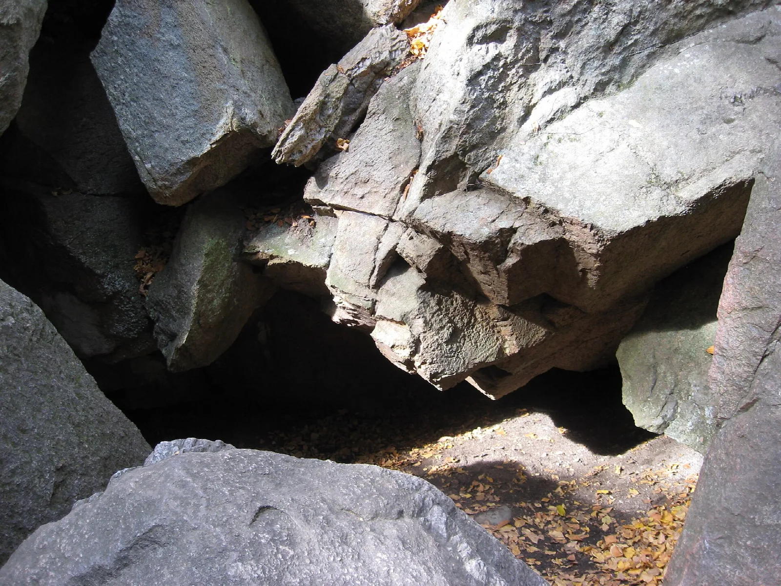 Large broken gray boulders forming a low cave opening