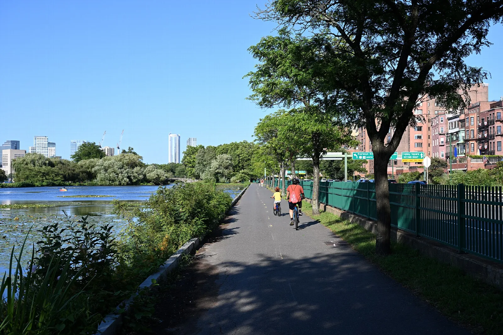 A paved path with cyclists beside water and trees