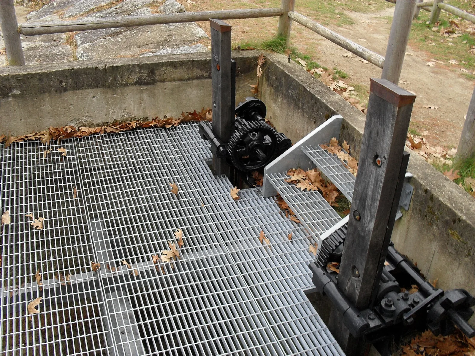 A metal grate over a canal gate with iron mechanisms