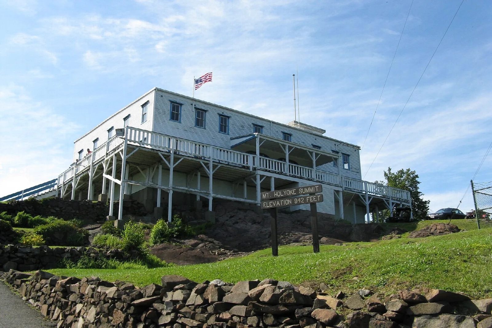 A large white hilltop building with a long porch against a blue sky