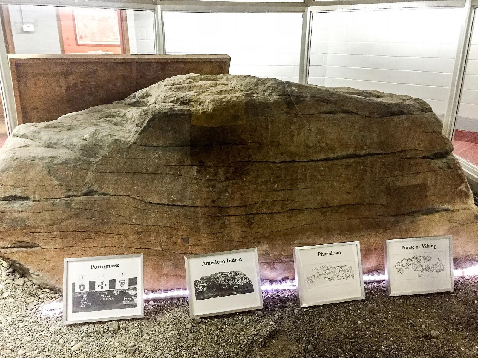 A large carved rock displayed indoors with small information cards