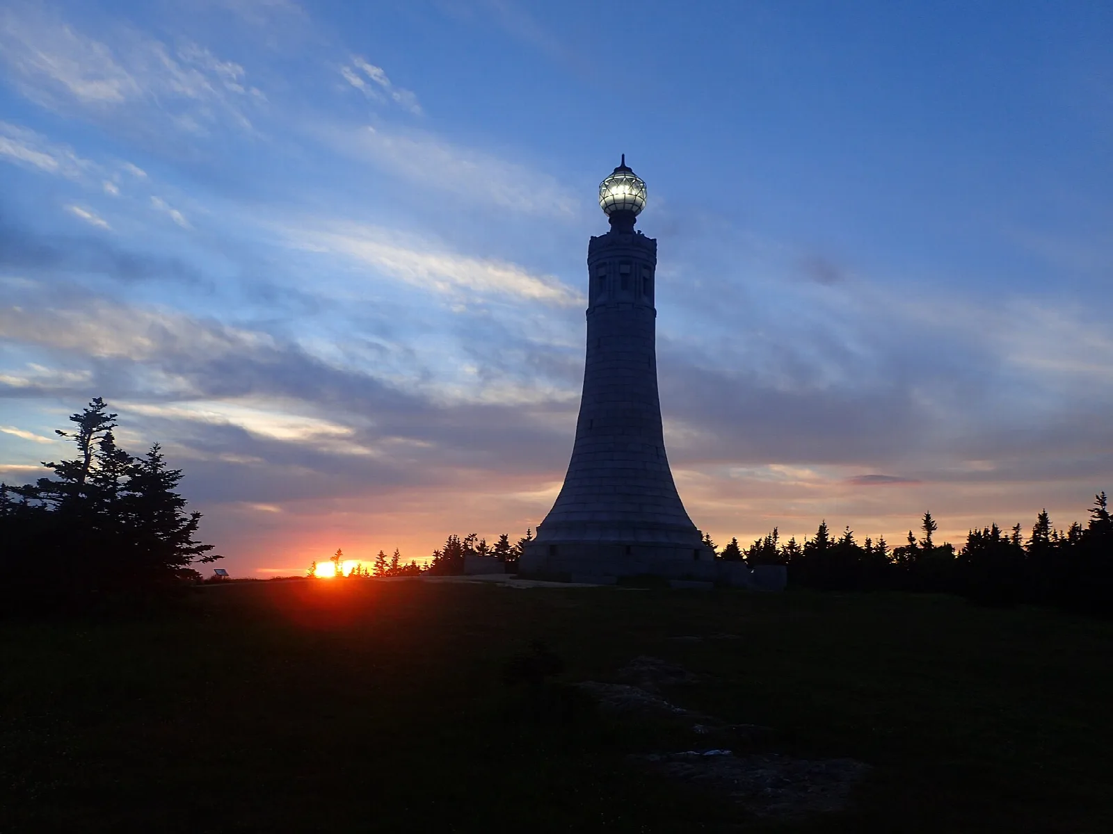 A tall stone tower lit at sunset against a blue and orange sky