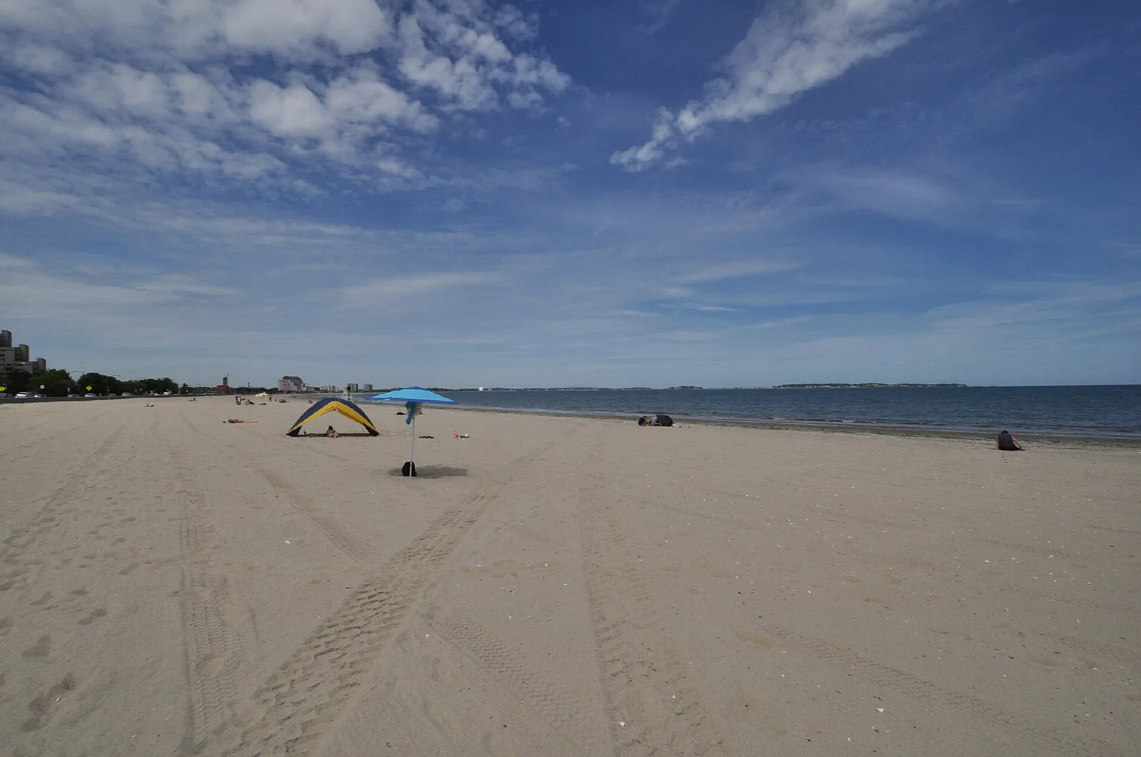 A wide empty sandy beach under blue sky and clouds