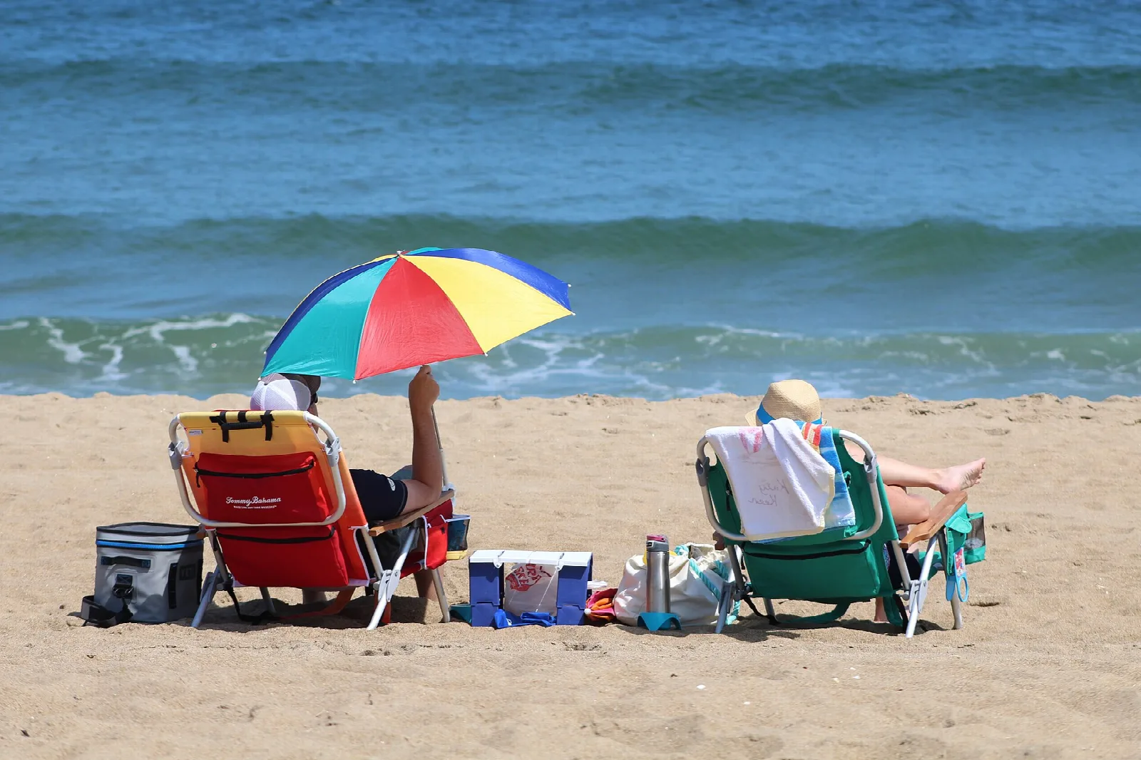 Two beach chairs and an umbrella facing the ocean waves