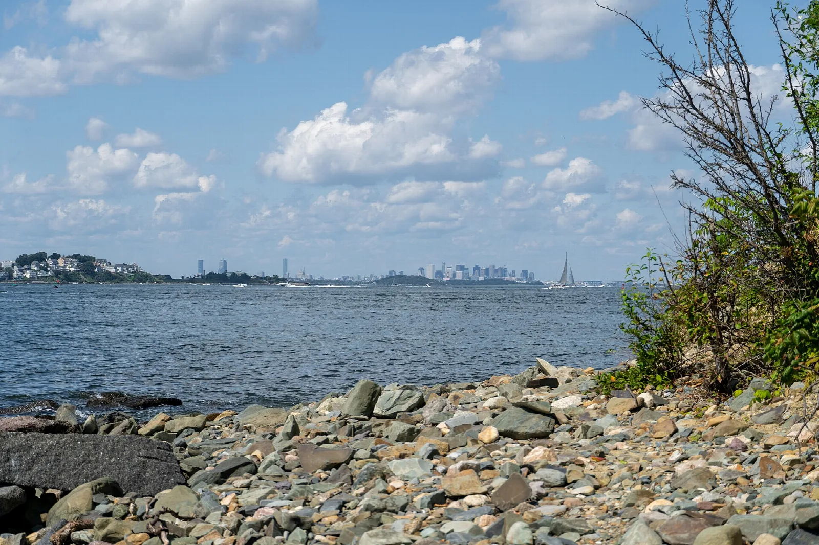 A rocky beach looking across the bay to a distant city skyline