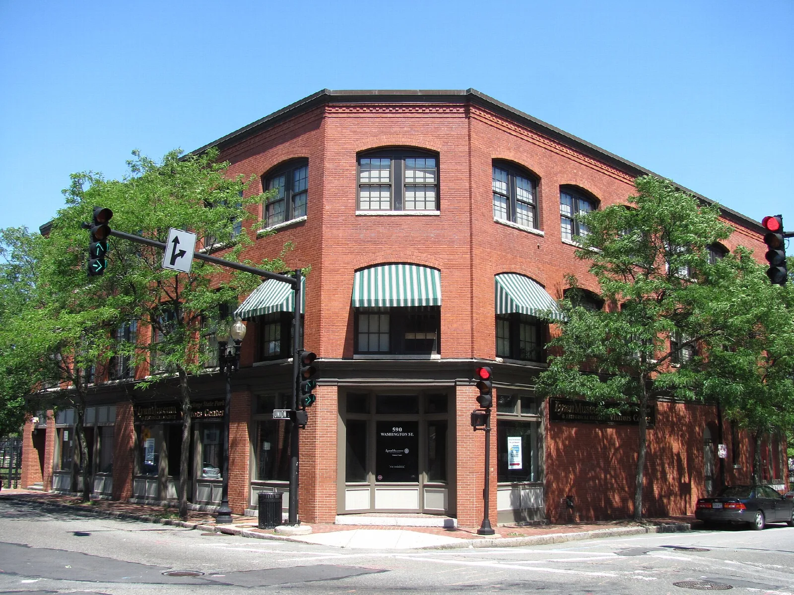A red brick building at a street corner with striped awnings