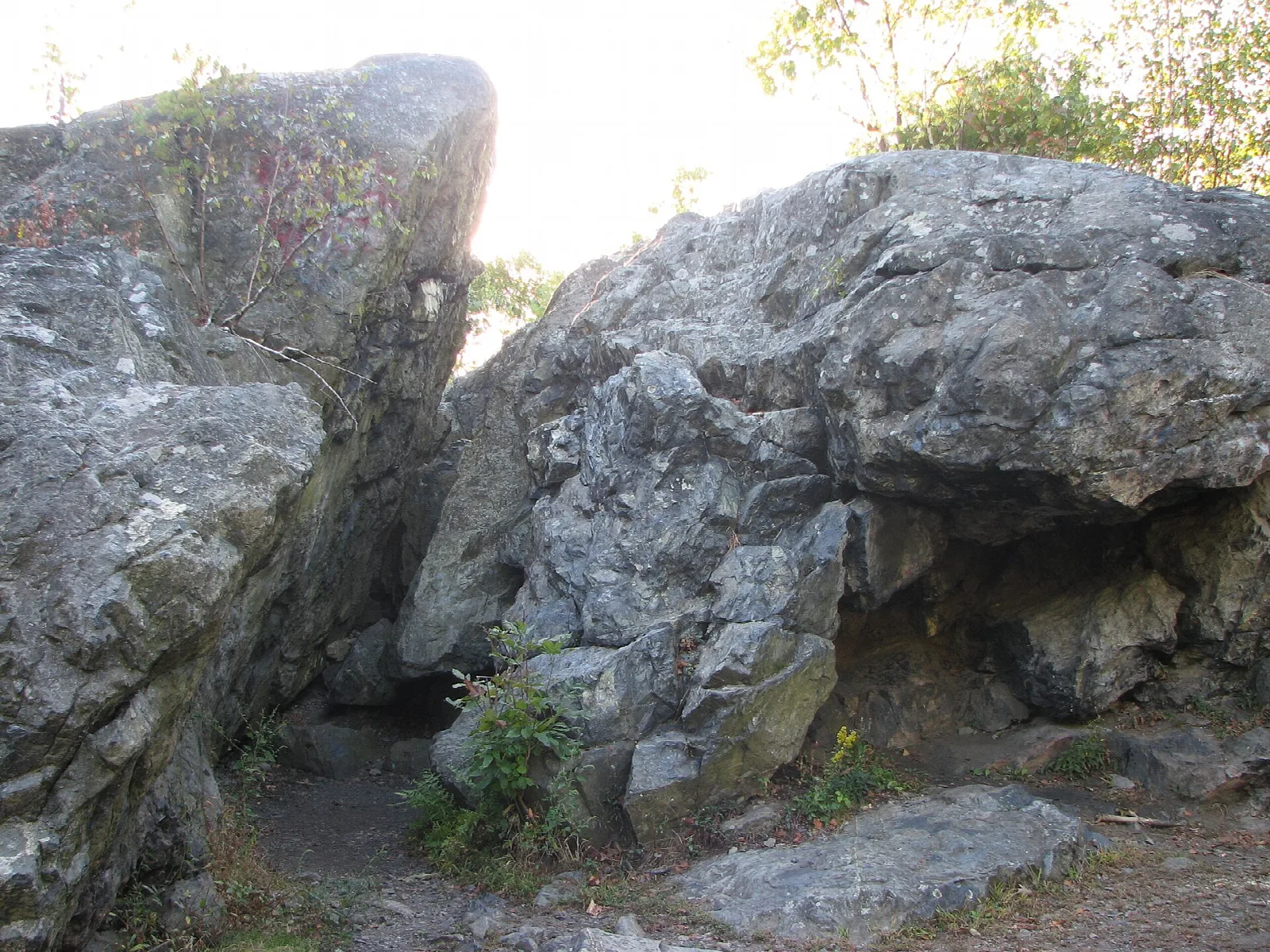 Two large gray boulders with a gap forming a small cave