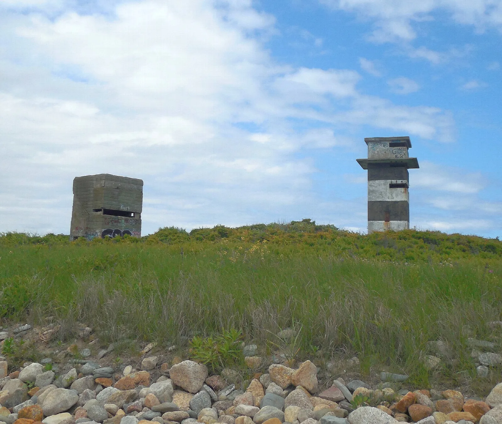 Two concrete watchtowers above a grassy rise