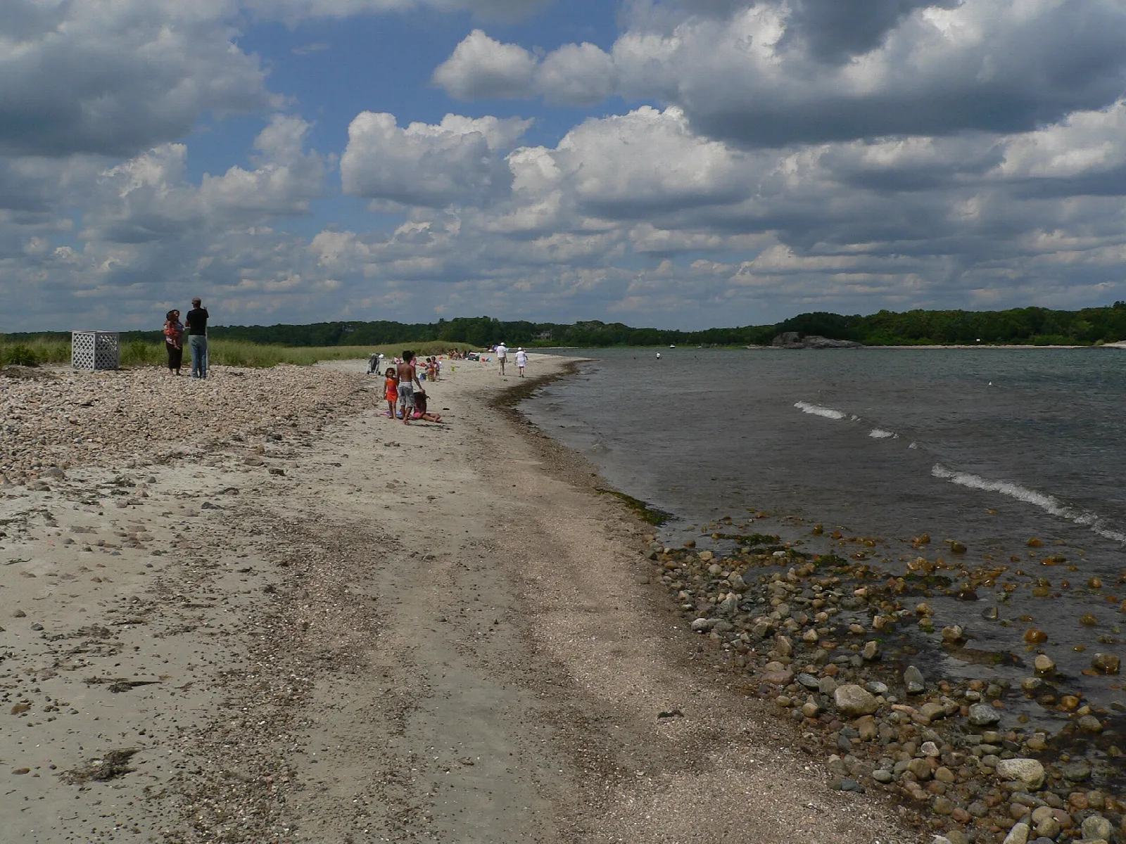 A narrow sandy spit with water on both sides and distant people