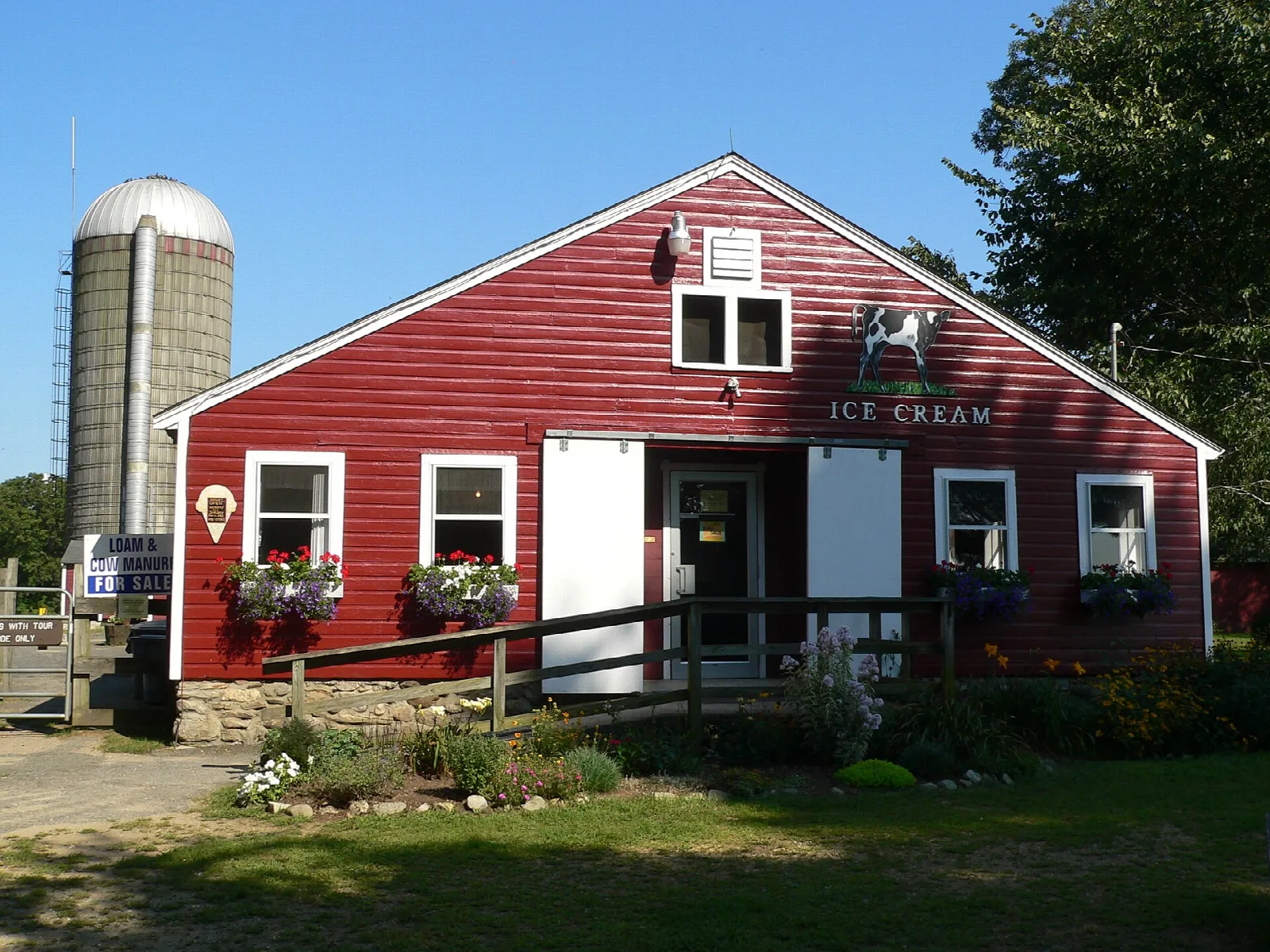 Red farm building with a silo and flower boxes