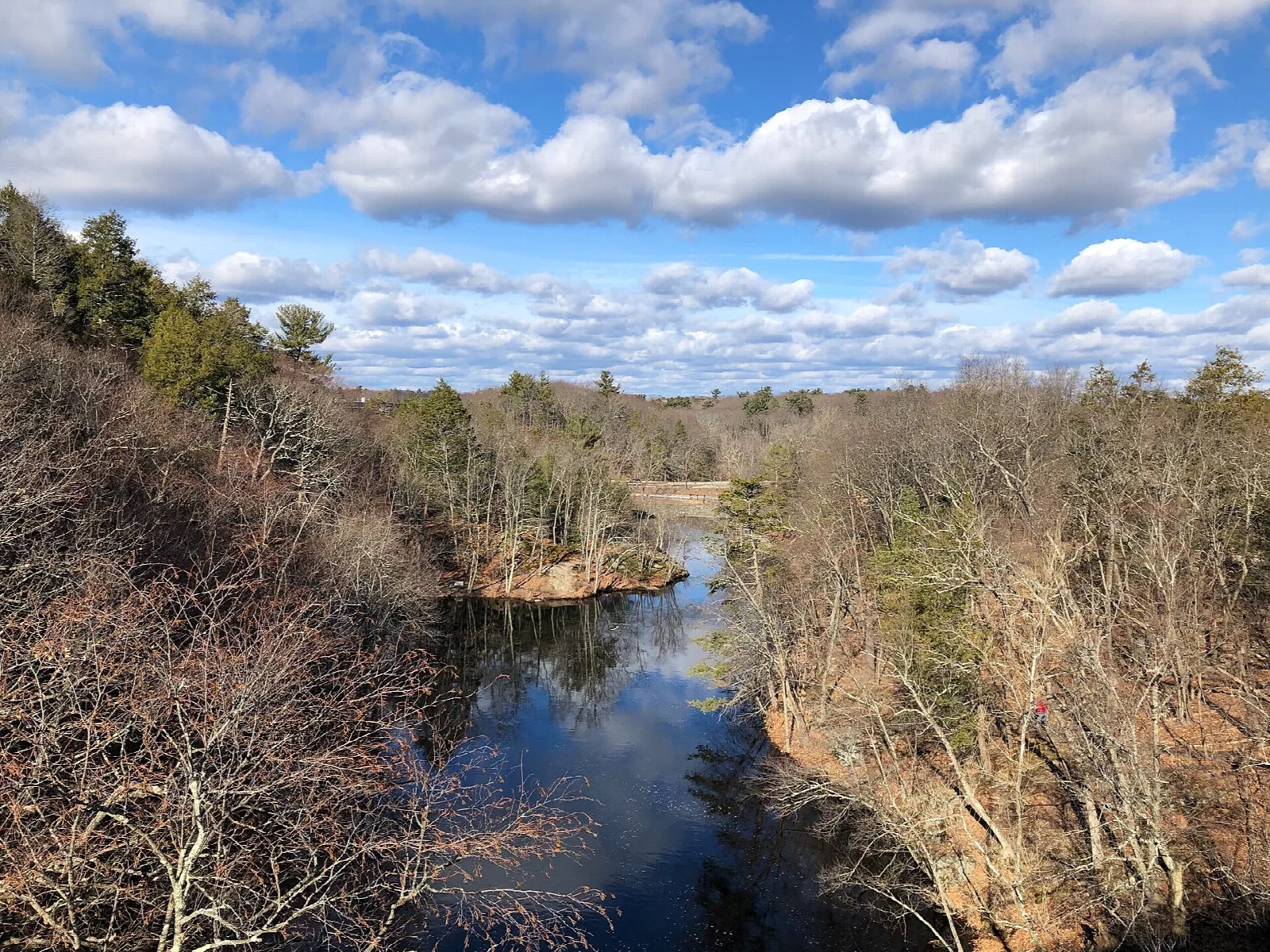 River winding between wooded banks under a blue sky with clouds