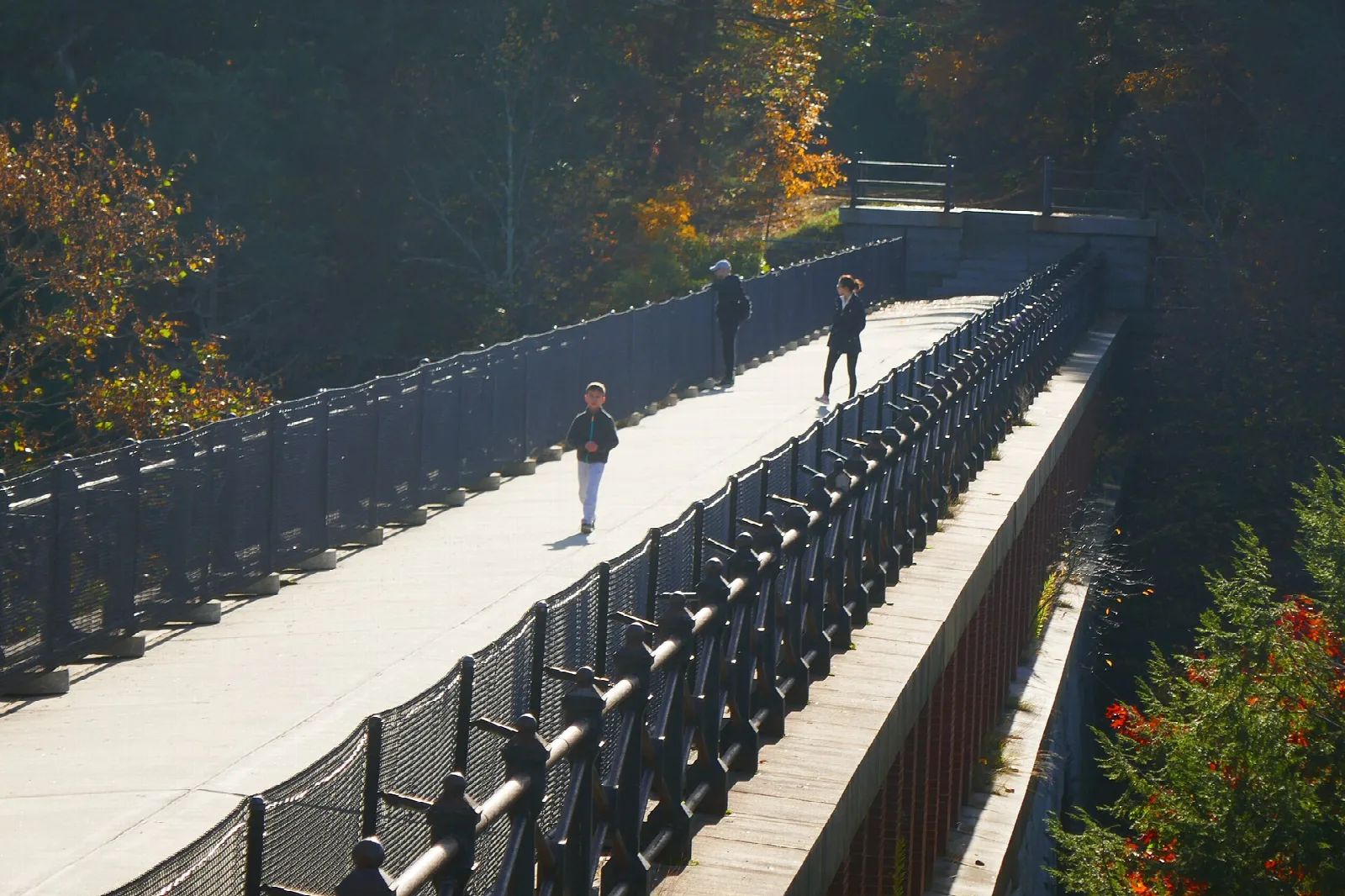 Wide bridge walkway with iron railings and people crossing