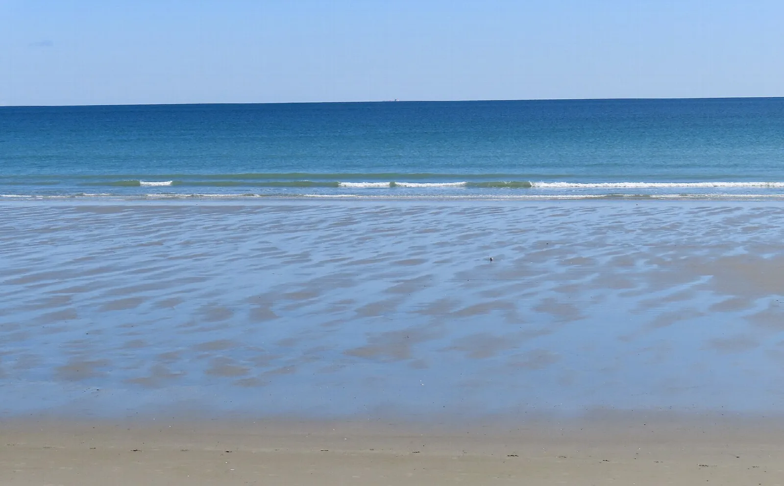 Blue ocean behind a smooth golden sand beach