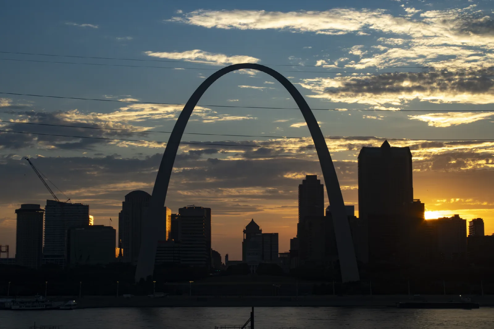 The arch and downtown towers in silhouette against a golden sunset sky