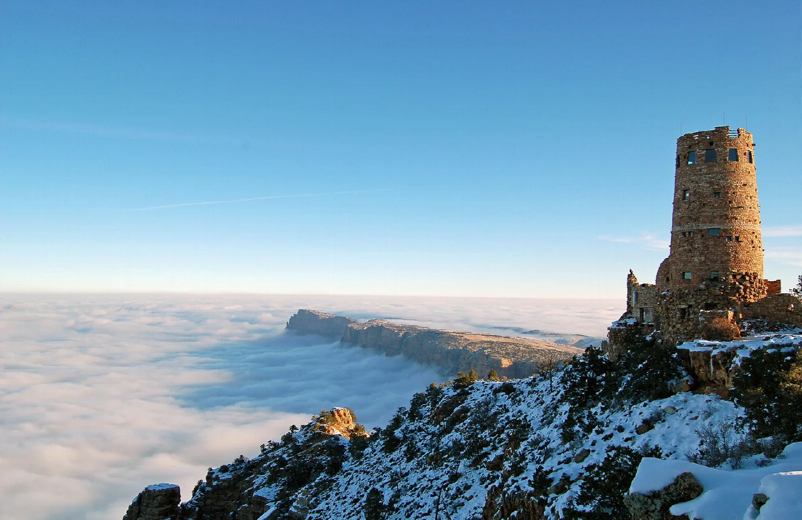 The stone Desert View Watchtower on the rim above a canyon filled with a sea of clouds