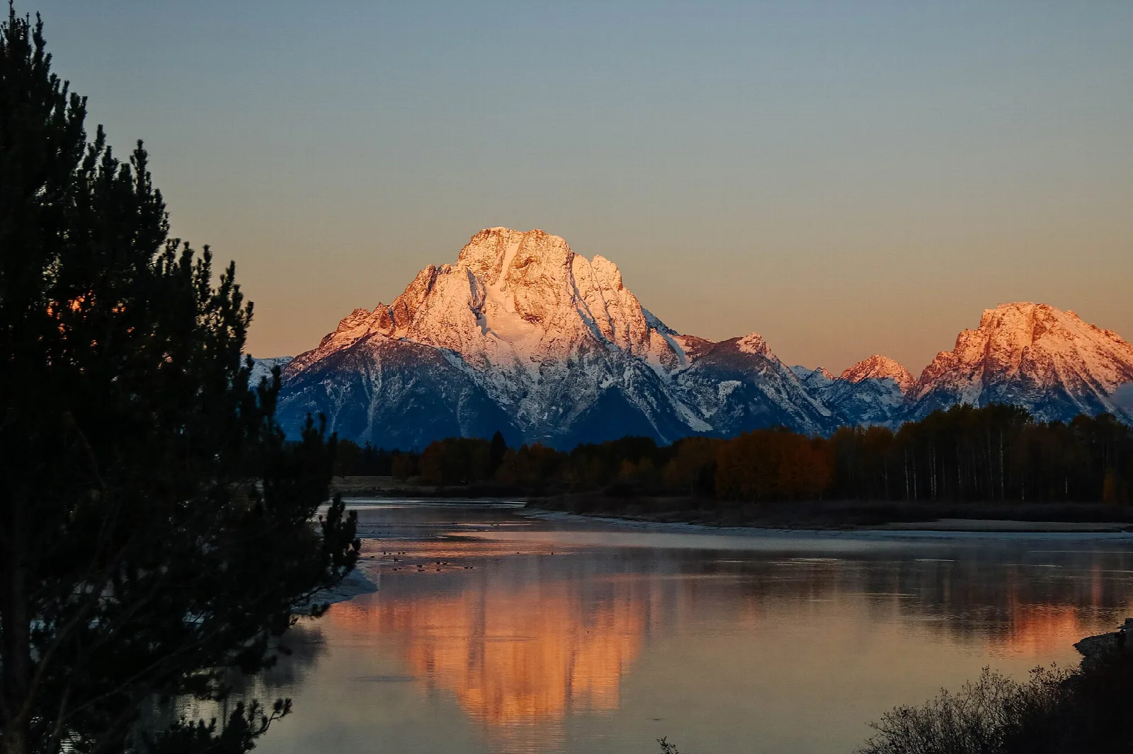 Mount Moran glowing at sunrise, reflected in the still Snake River