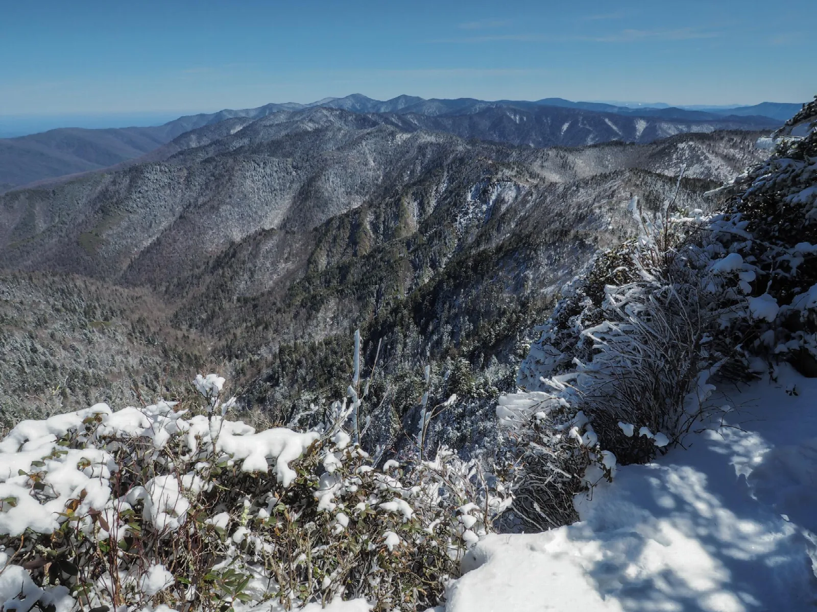 A clear sky with a vast snowy mountain scene.