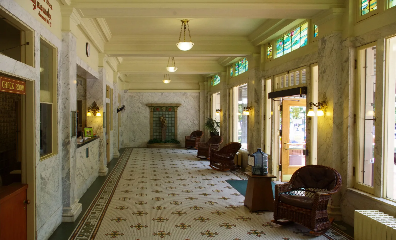 An elegant bathhouse lobby with stained-glass skylights, tiled floor and wicker chairs