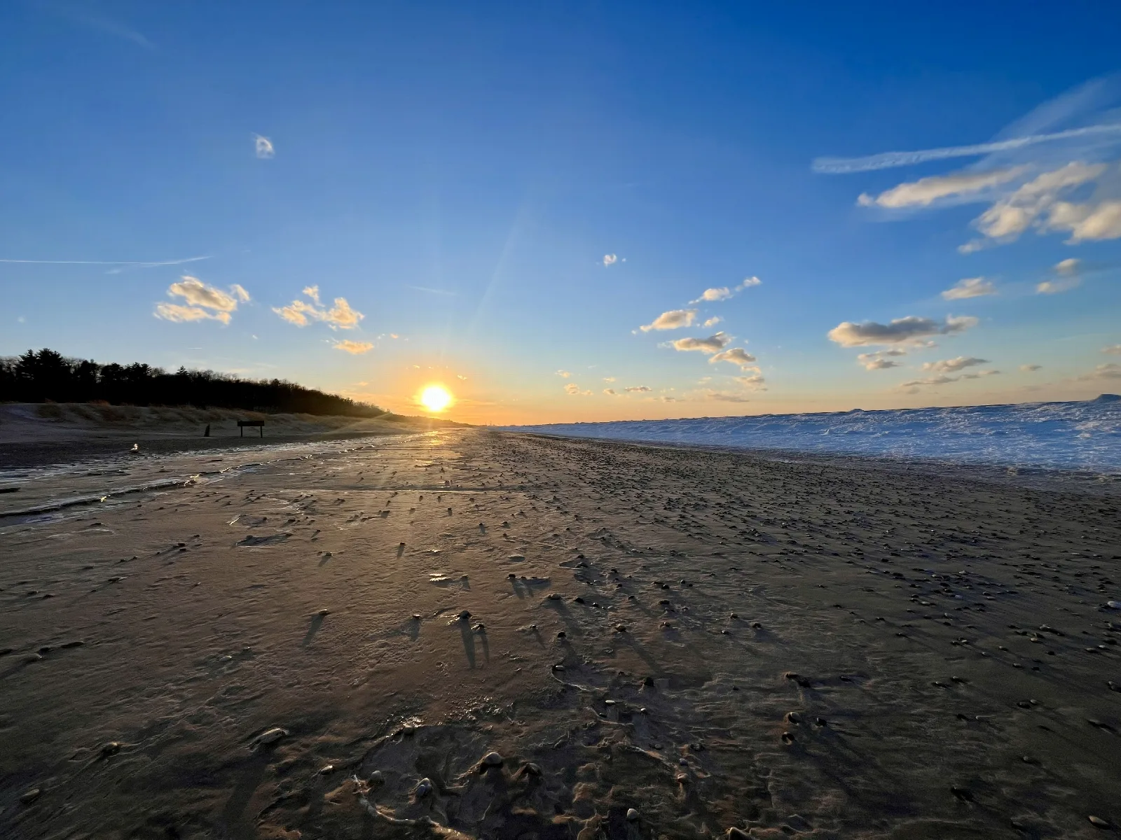 The setting sun over a wide beach and Lake Michigan shoreline