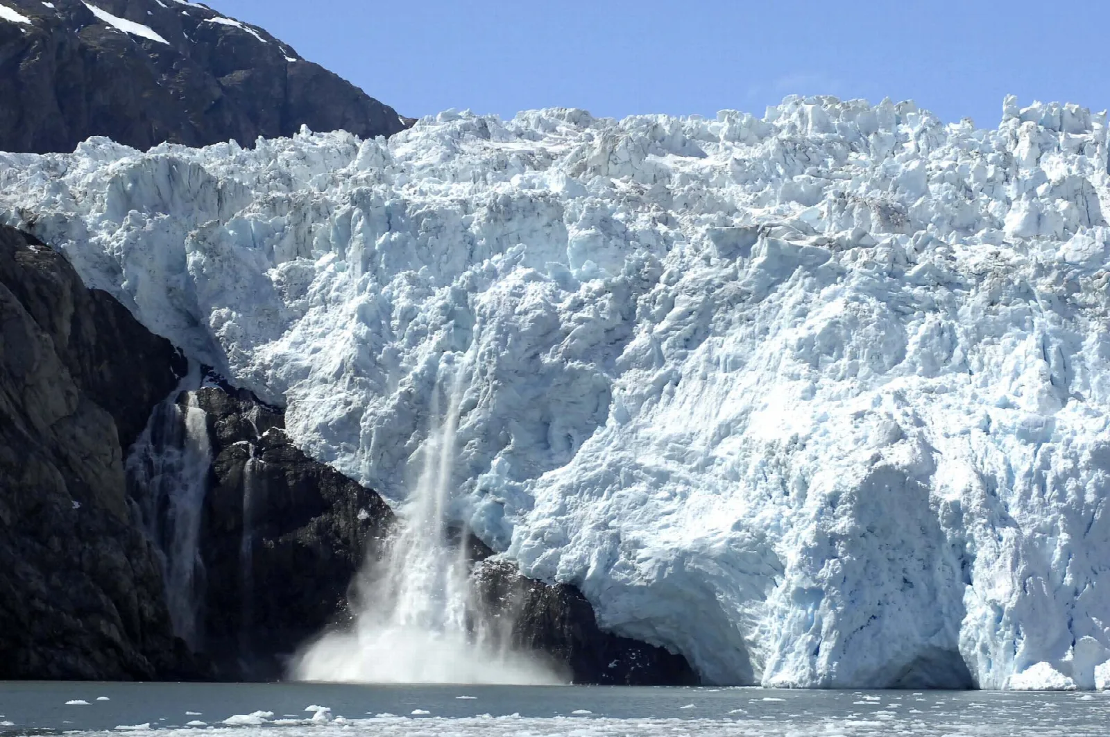 Ice crashing into the sea from the blue-white face of a tidewater glacier
