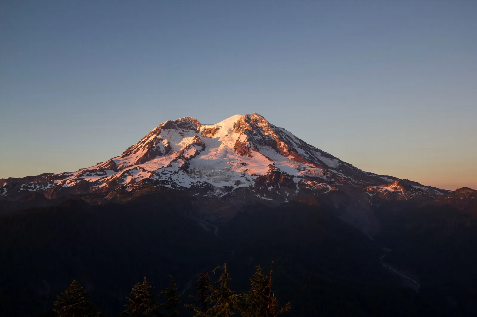 The summit glowing pink and orange against a clear evening sky