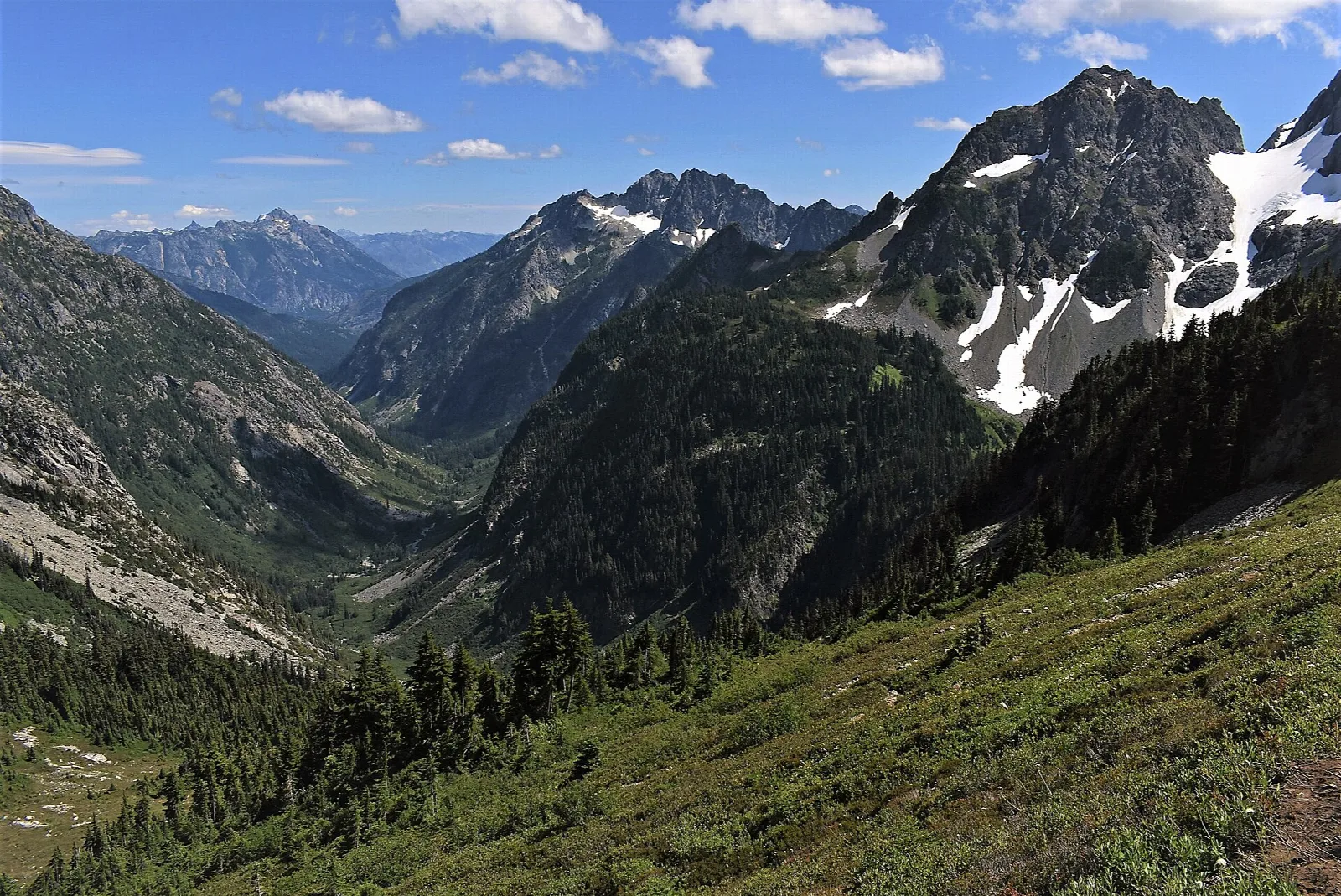 Rugged peaks above deep forested valleys under a blue sky