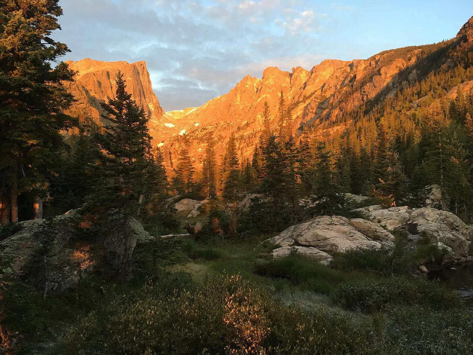 Sheer cliffs lit gold at sunrise above an alpine basin