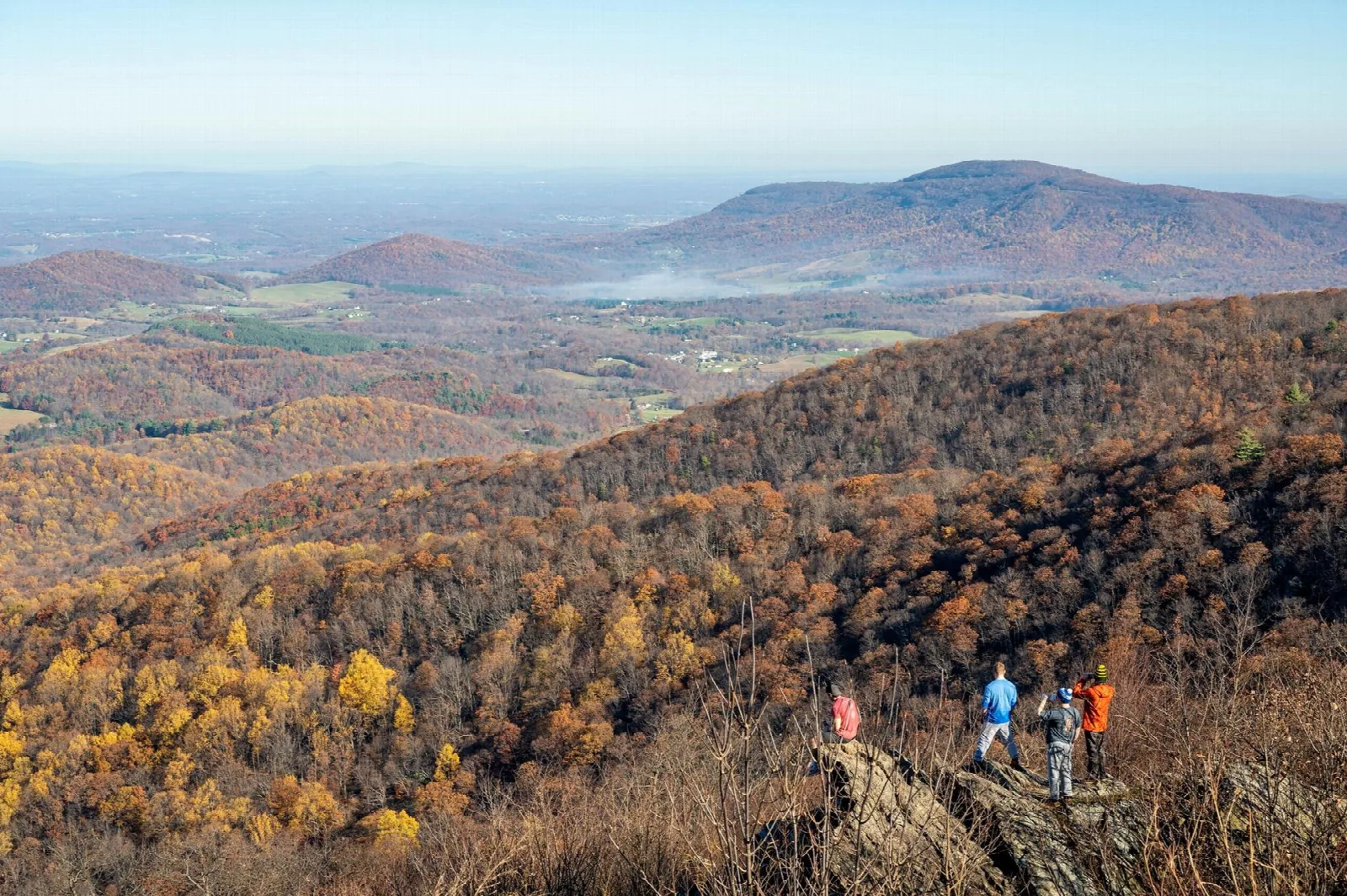 Autumn-colored ridges rolling toward a distant mountain under blue sky